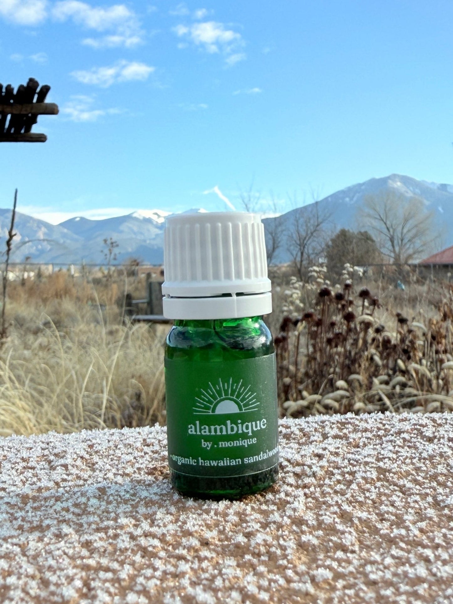 organic royal Hawaiian sandalwood essential oil •the • alambique. green essential oil bottle on bench with white cap