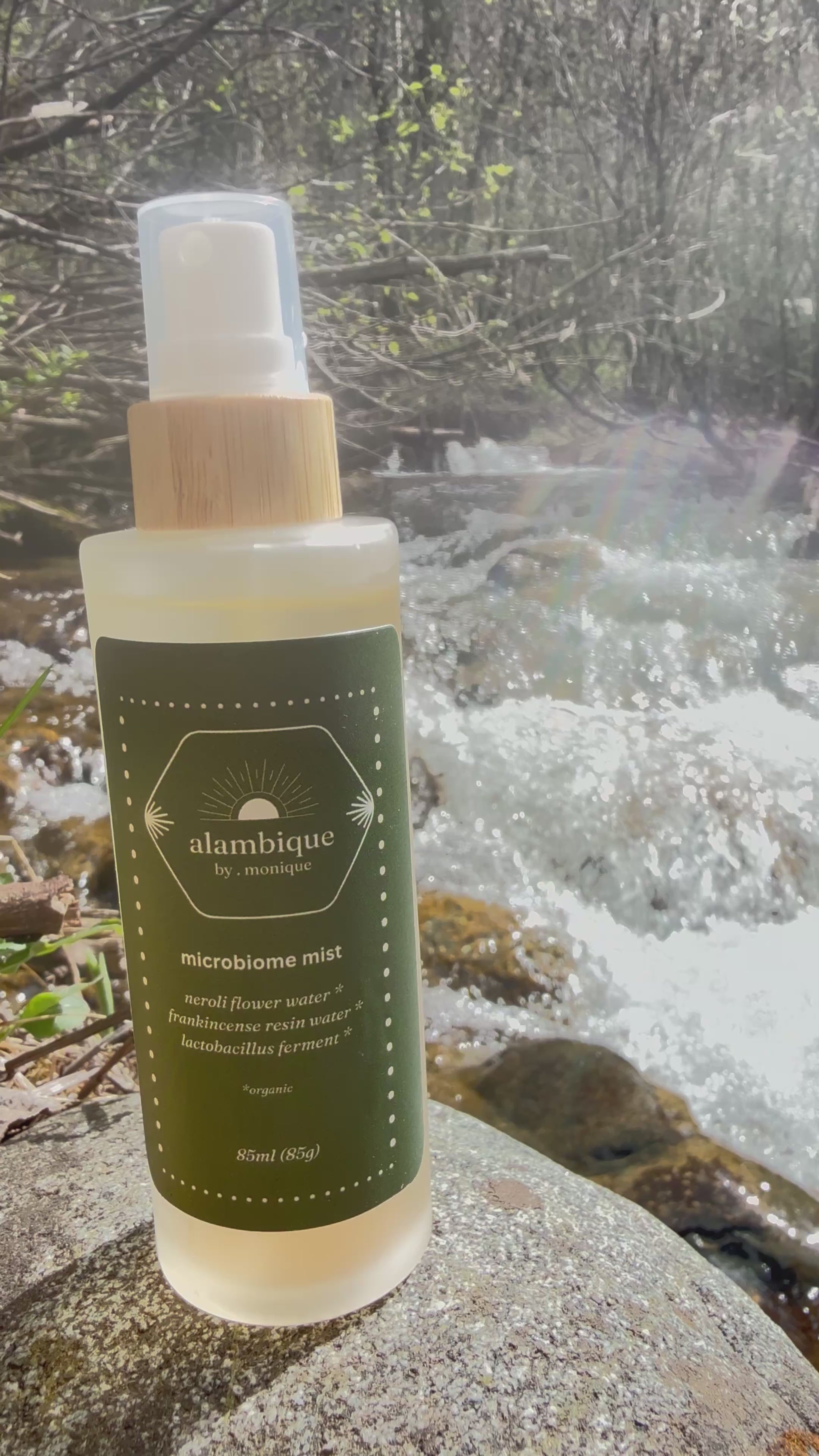 Certified organic barrier repair face mist by the alambique, containing neroli and frankincense hydrosols, set against a pristine flowing river.
