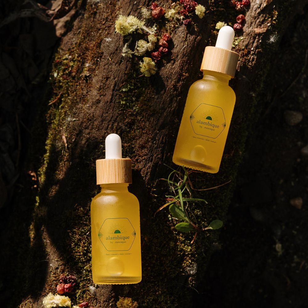 the best ethical bee venom skin serum sitting in nature on a log with helichrysum flowers